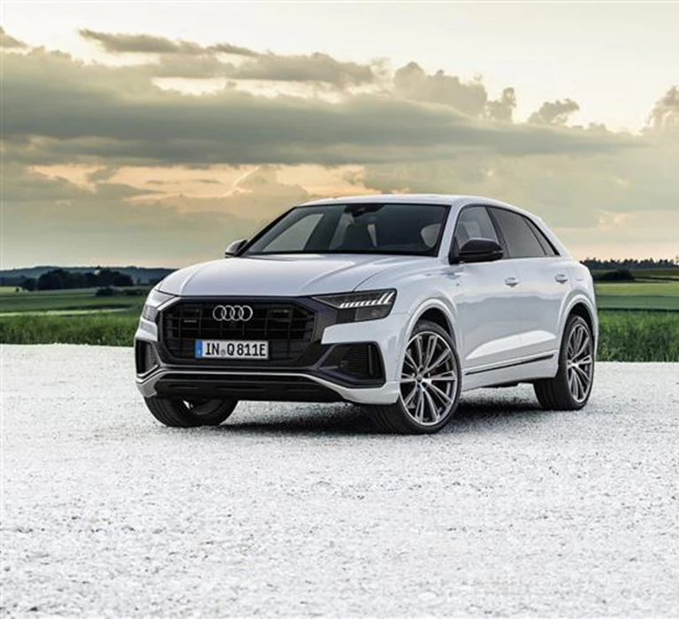 Picture of a white audi car on white gravel with a green field in the background